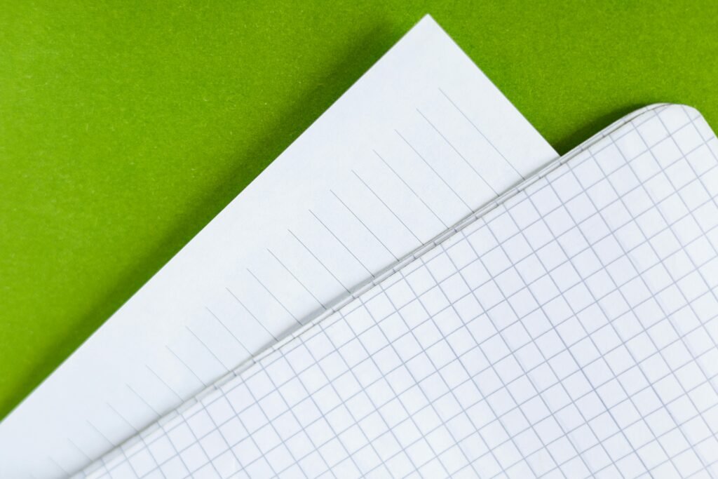 Close-Up of Lined and Graph Paper Over Green Background